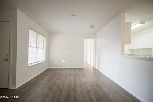 unfurnished room featuring a textured ceiling and dark hardwood / wood-style flooring