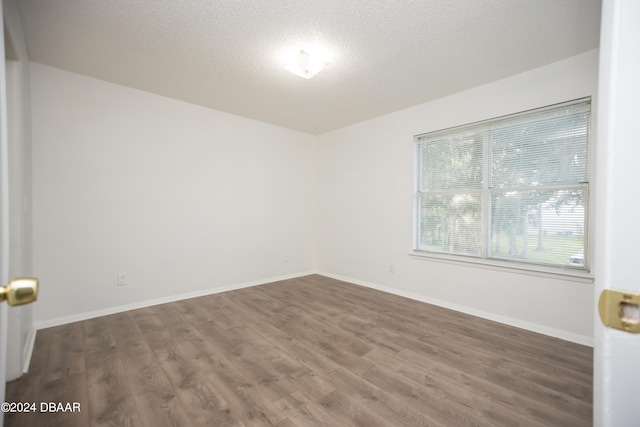 empty room featuring dark wood-type flooring and a textured ceiling