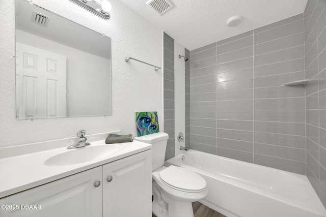 bathroom with washtub / shower combination, toilet, a textured ceiling, vanity, and a textured wall