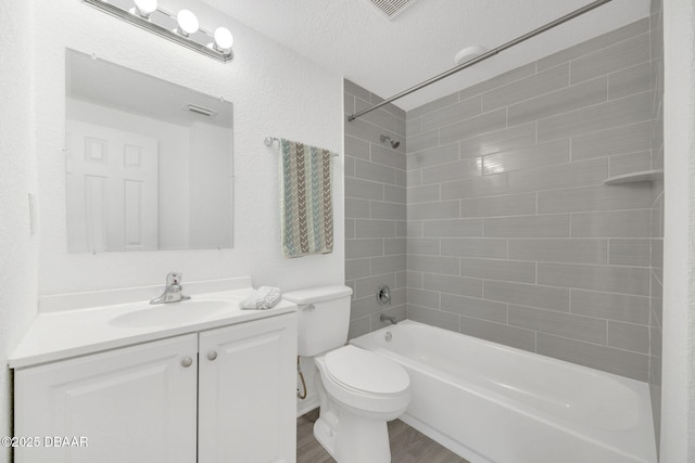bathroom featuring washtub / shower combination, toilet, vanity, wood finished floors, and a textured ceiling