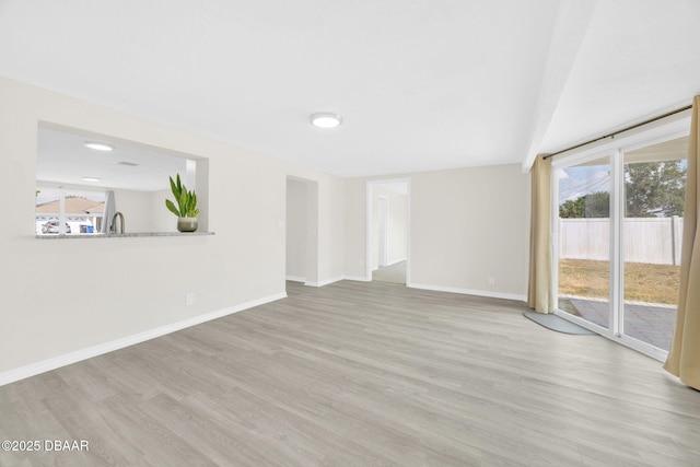unfurnished living room featuring light wood-style flooring and baseboards