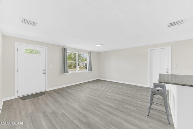 unfurnished living room with light wood-type flooring and baseboards