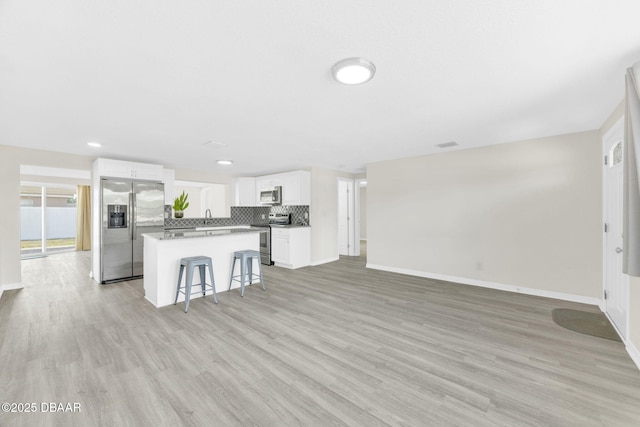 unfurnished living room with baseboards, light wood-style flooring, a sink, and recessed lighting