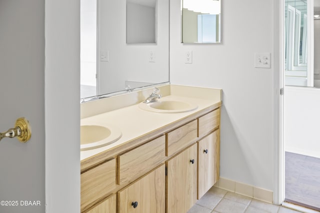 bathroom with tile patterned flooring, a sink, baseboards, and double vanity