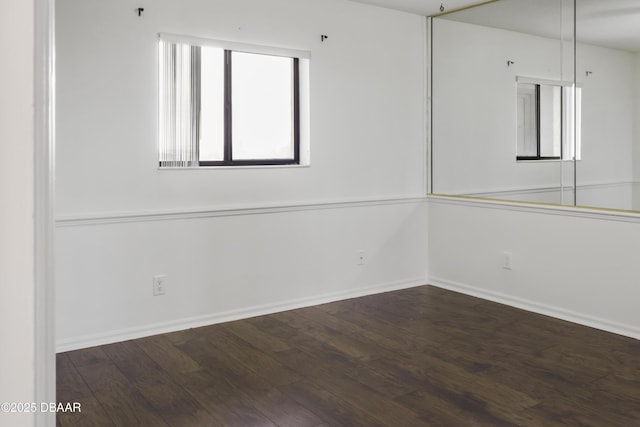 unfurnished room with dark wood finished floors and baseboards