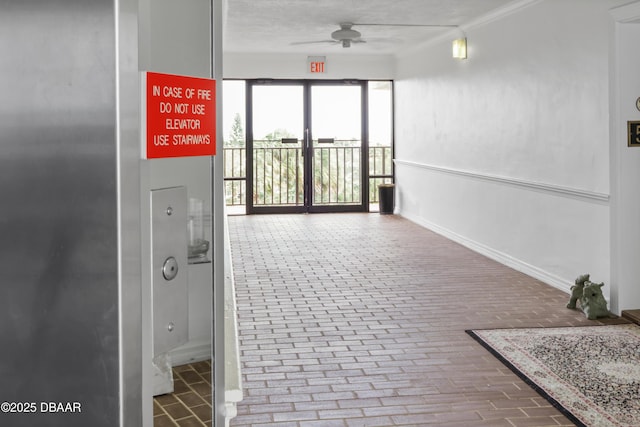 corridor featuring brick floor and baseboards