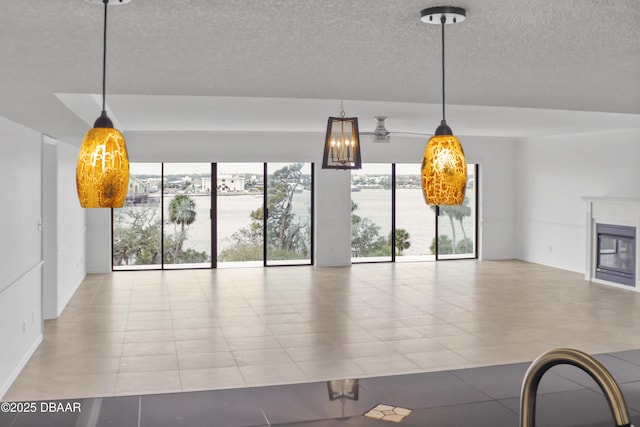 unfurnished living room with a textured ceiling, a glass covered fireplace, and a healthy amount of sunlight