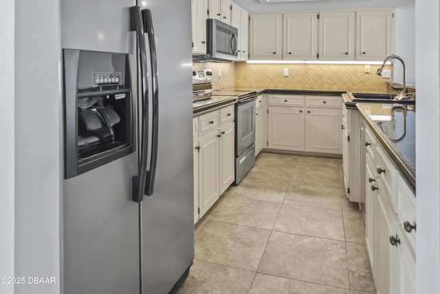 kitchen featuring light tile patterned floors, white cabinets, dark countertops, stainless steel appliances, and backsplash