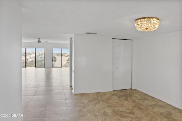 empty room featuring ceiling fan with notable chandelier, a textured ceiling, visible vents, and baseboards