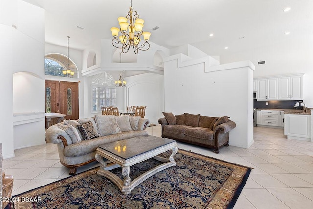 tiled living room featuring sink, a towering ceiling, and an inviting chandelier