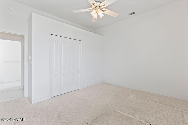 unfurnished bedroom featuring ceiling fan, a closet, and light carpet