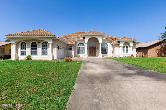 mediterranean / spanish home featuring a garage and a front yard