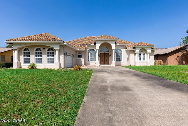 mediterranean / spanish-style house with a front yard and a garage