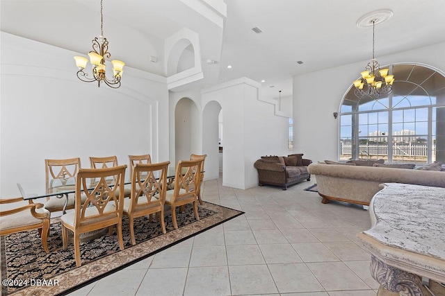 dining space with a towering ceiling, a notable chandelier, and light tile patterned flooring