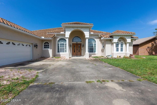 mediterranean / spanish house with a garage and a front lawn