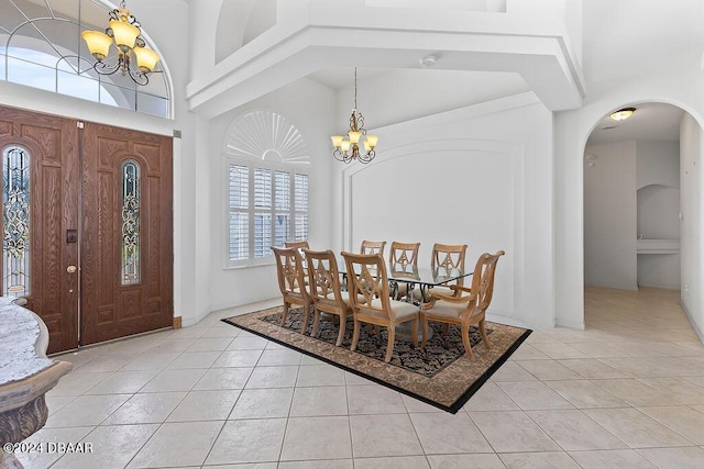 entrance foyer with a notable chandelier, light tile patterned flooring, and a towering ceiling