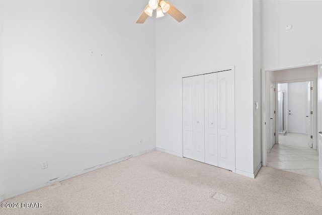 unfurnished bedroom featuring light carpet, a closet, and ceiling fan