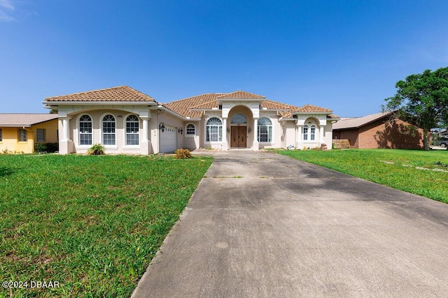 mediterranean / spanish-style house featuring a front yard and a garage