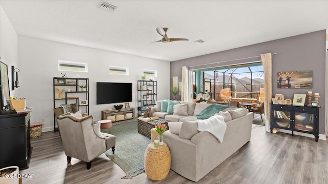 living room featuring hardwood / wood-style flooring, a textured ceiling, and ceiling fan