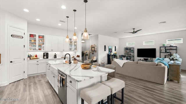 kitchen with a center island with sink, white cabinetry, sink, and stainless steel dishwasher