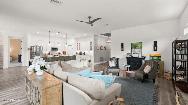 living room with ceiling fan and light hardwood / wood-style flooring