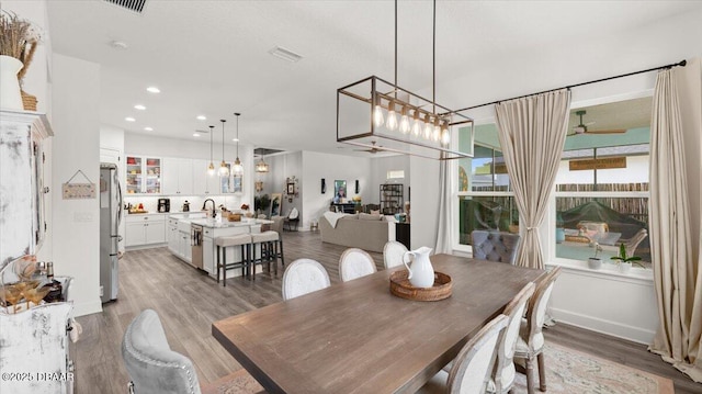 dining area featuring ceiling fan, sink, and light wood-type flooring