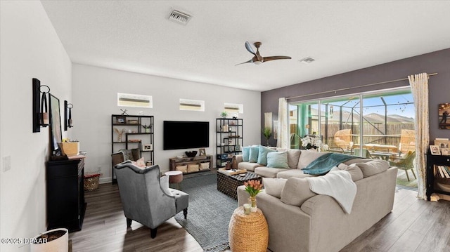 living room featuring a textured ceiling, dark wood-type flooring, and ceiling fan