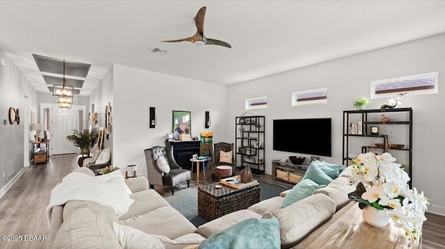 living room with ceiling fan with notable chandelier and hardwood / wood-style floors