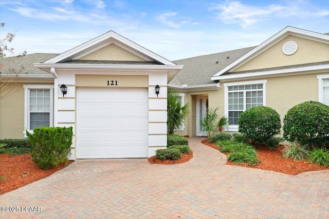 ranch-style home with decorative driveway, an attached garage, and stucco siding