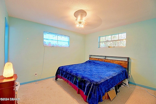 bedroom with a textured ceiling, carpet floors, a ceiling fan, and baseboards