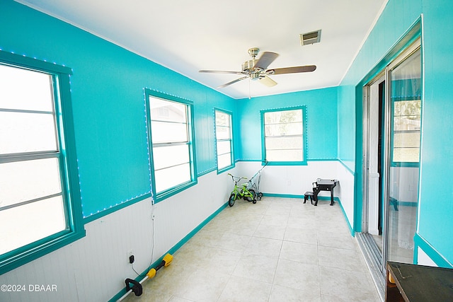 interior space featuring a ceiling fan, visible vents, baseboards, and light tile patterned floors