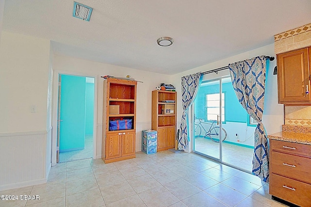 interior space featuring light tile patterned floors, visible vents, and wainscoting