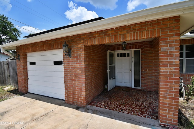 property entrance with a garage, driveway, and brick siding