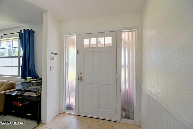 entrance foyer featuring wainscoting, a textured wall, and light tile patterned flooring