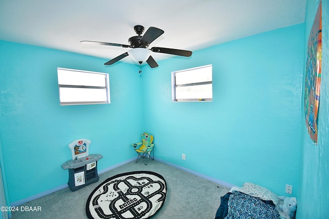 interior space with light colored carpet, multiple windows, and ceiling fan