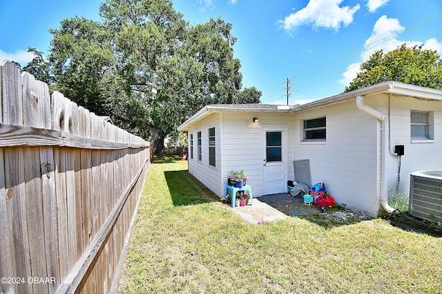 back of house with a lawn, cooling unit, and a fenced backyard