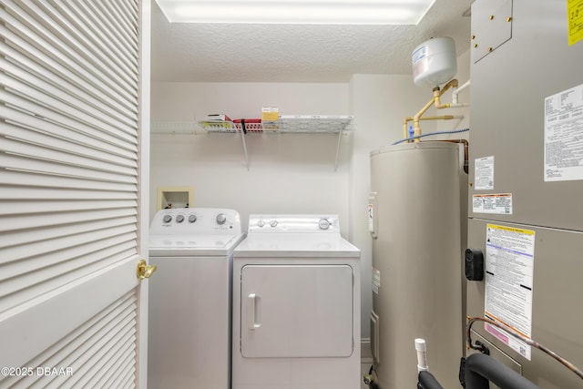 laundry area featuring a textured ceiling, laundry area, heating unit, electric water heater, and washer and clothes dryer
