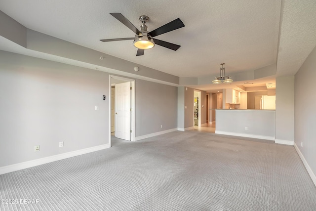 unfurnished living room with baseboards, a textured ceiling, a ceiling fan, and light carpet
