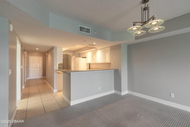 kitchen featuring white cabinetry, light colored carpet, baseboards, visible vents, and freestanding refrigerator