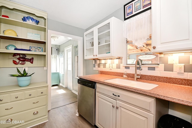 530 Ronnoc Ln, New Smyrna Beach, FL 32168 - kitchen with stainless steel dishwasher, a sink, light wood-type flooring, glass insert cabinets, and white cabinetry