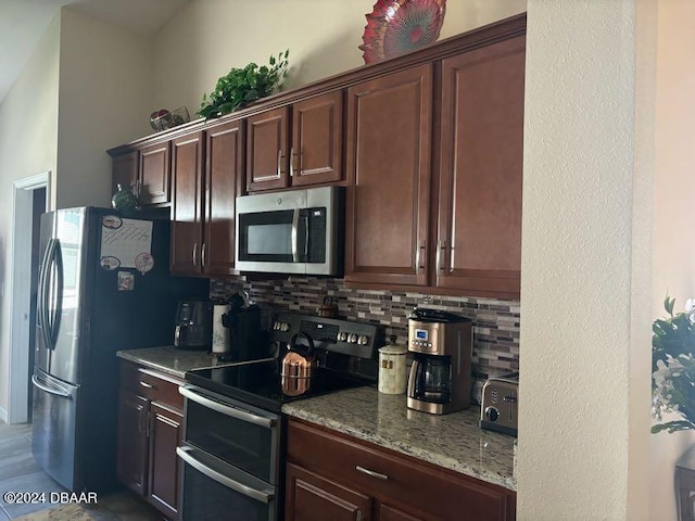 kitchen featuring light stone countertops, dark brown cabinetry, backsplash, and stainless steel appliances