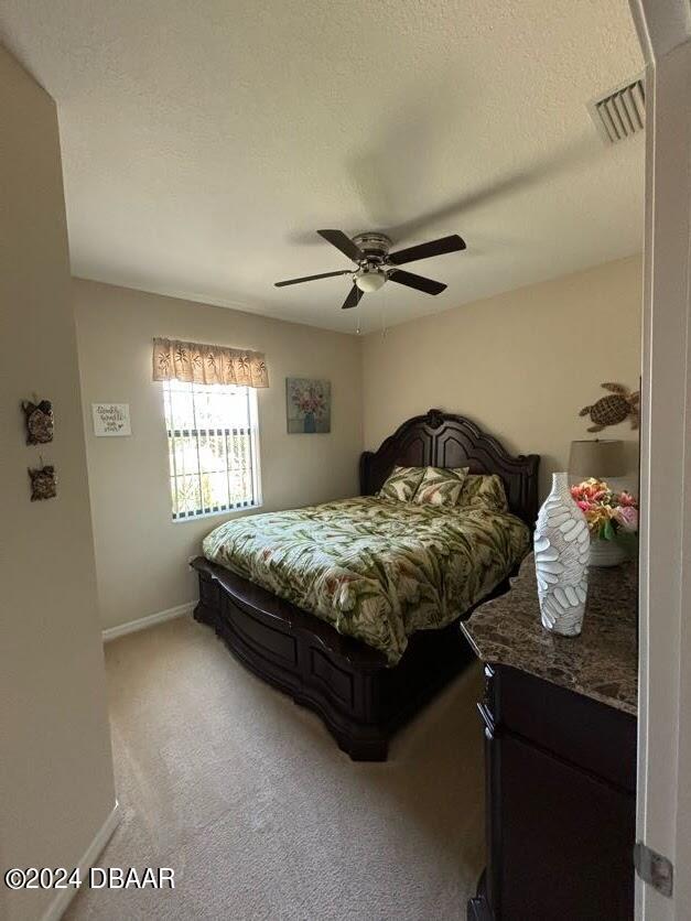 bedroom featuring ceiling fan, a textured ceiling, and carpet flooring