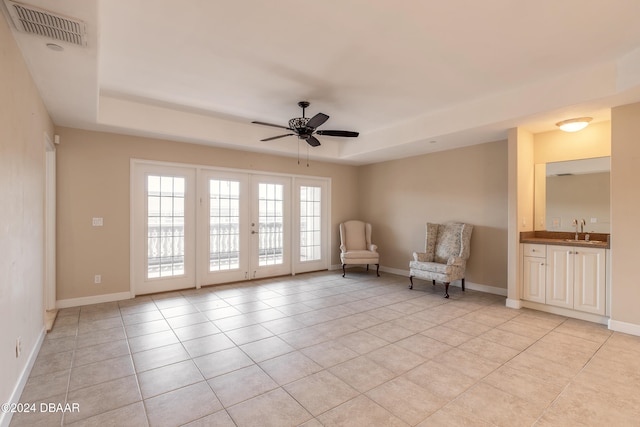 unfurnished room featuring sink, light tile patterned floors, ceiling fan, and a raised ceiling