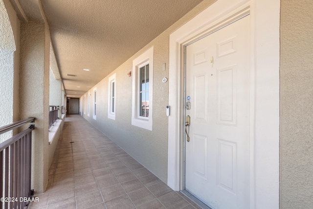 corridor featuring a textured ceiling and light tile patterned flooring