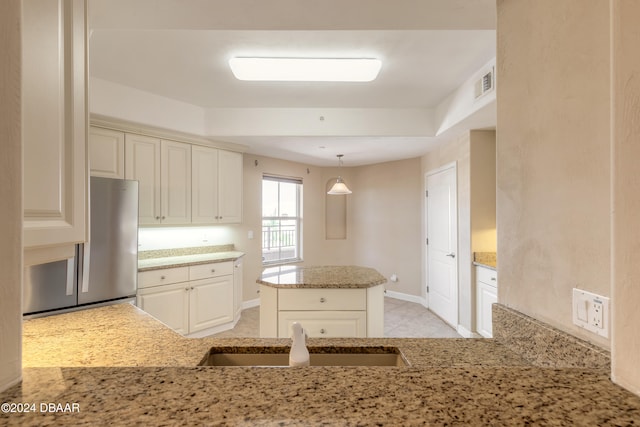 kitchen featuring cream cabinets, sink, light tile patterned flooring, decorative light fixtures, and stainless steel fridge