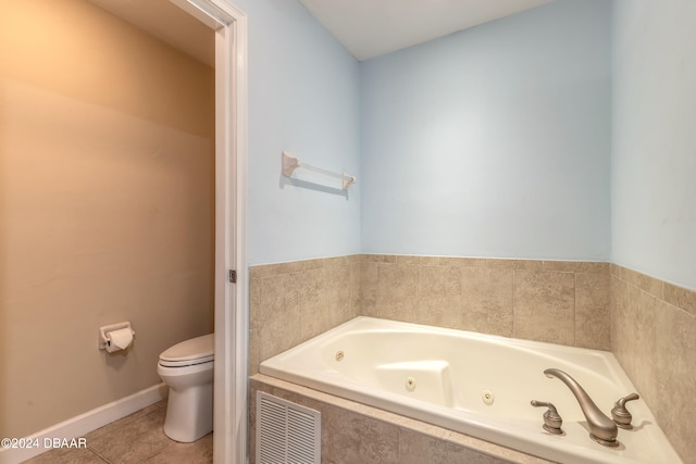 bathroom featuring tile patterned flooring, tiled tub, and toilet