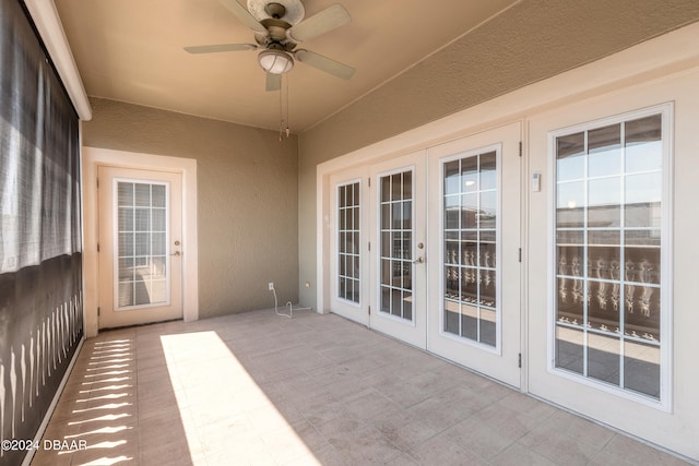 unfurnished sunroom featuring ceiling fan and french doors