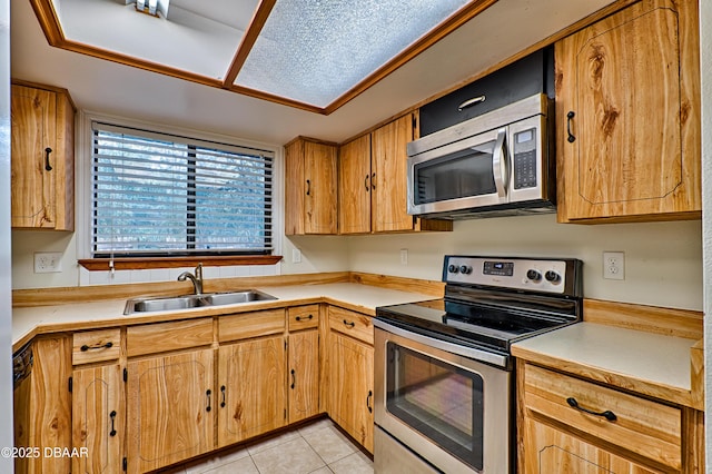 kitchen with appliances with stainless steel finishes, light countertops, a sink, and light tile patterned floors