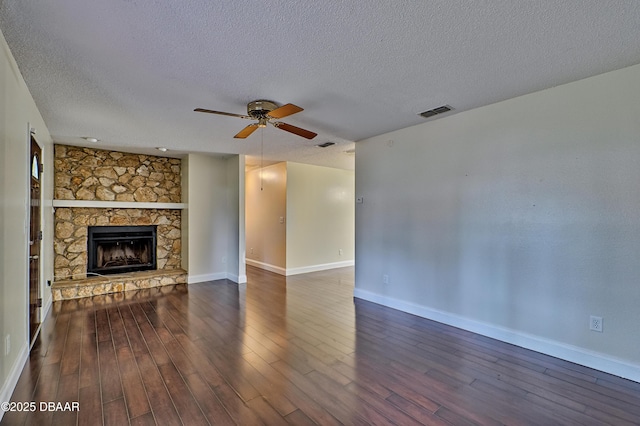 unfurnished living room with dark wood-style floors, a fireplace, visible vents, a ceiling fan, and baseboards