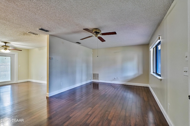 unfurnished room featuring baseboards, ceiling fan, visible vents, and dark wood-type flooring